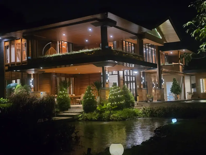 The Grand Villa lit up at night beside its pond