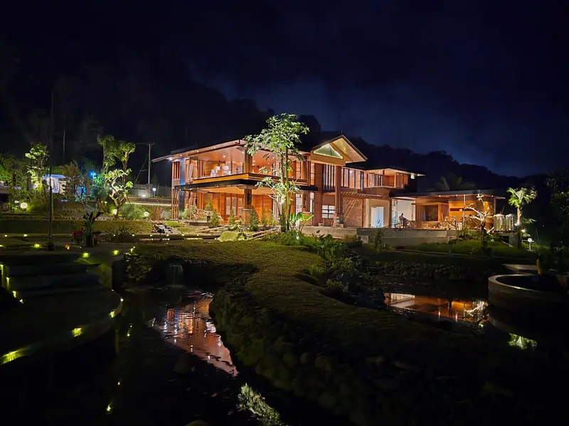 The Grand Villa glowing beside the water garden at night