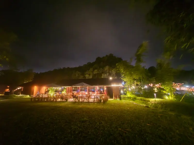 The restaurant pavilion glowing across the lawn at night