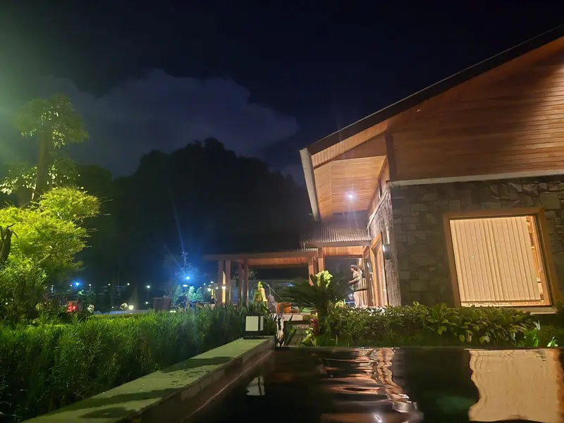A stone-and-timber villa beside a reflecting pool at night